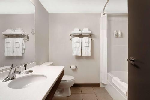 a white bathroom with a sink and a toilet at Days Inn by Wyndham Victoria Airport Sidney in Sidney