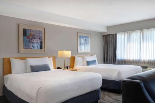 a hotel room with two beds and a couch at Days Inn by Wyndham Victoria Airport Sidney in Sidney