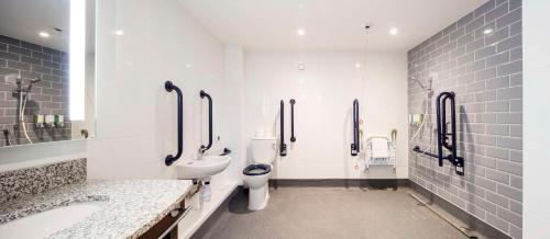 a white bathroom with two toilets and a sink at Hampton By Hilton Humberside Airport in Kirmington