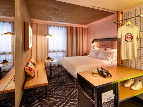 パリにあるMama Shelter Paris Westの大きなベッドとテーブルが備わるホテルルームです。