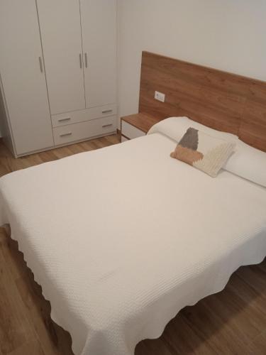 1 dormitorio con cama blanca y cabecero de madera en La casa del timón primer piso, 