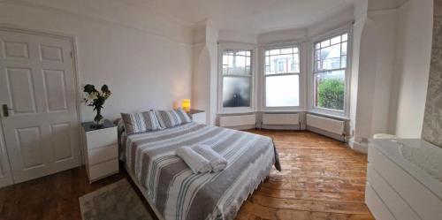 ein weißes Schlafzimmer mit einem Bett und zwei Fenstern in der Unterkunft Peaceful well equipped flat near central London in London
