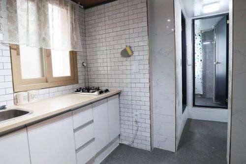 eine weiße Küche mit einem Waschbecken und einem Fenster in der Unterkunft Gu & Anne House Sinchon in Seoul