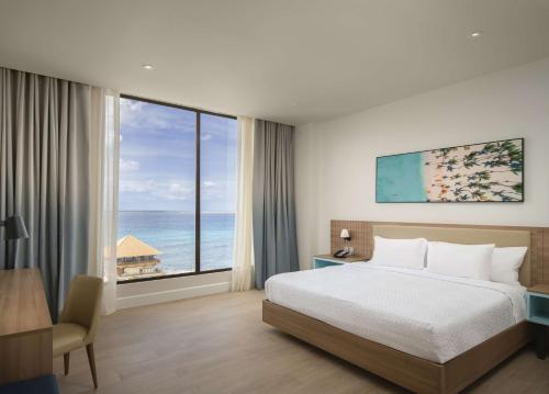 Hilton Garden Inn La Romana في لا رومانا: غرفة نوم مع سرير وإطلالة على المحيط