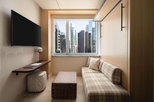 a living room with a couch and a large window at Motto By Hilton New York City Times Square in New York