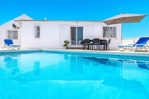 einen Pool mit Stühlen, einem Tisch und einem Sonnenschirm in der Unterkunft Villa Oahu by Algarve Vacation in Albufeira