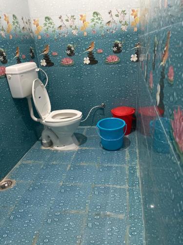 a bathroom with a toilet and a mural on the wall at Karma Hostel in Khajurāho