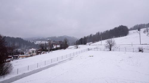 a snow covered field with a fence and a hill at Apartament Spokojna 18 in Wisła