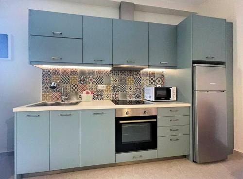 uma cozinha com armários azuis e um micro-ondas em Varsamos em Yiannioú