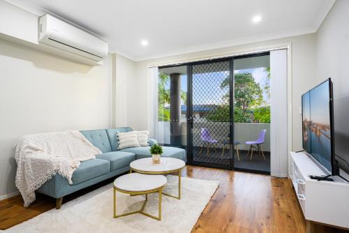 a living room with a blue couch and a tv at Parramatta New 2Bedroom apt close to TrainShoping in Sydney