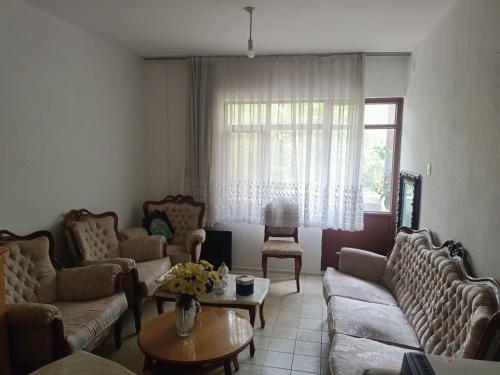 a living room with couches and a table and a window at Bahçeli Ev Müstakil in Burhaniye
