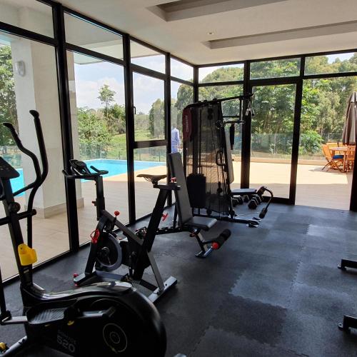 un gimnasio con cintas de correr y bicicletas estáticas frente a una piscina en Intercultural Apartment Nairobi Two Rivers, en Nairobi