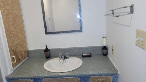 een badkamerbar met een wastafel en een spiegel bij Cozy quiet place next to hwy smart tv+wifi+netflix in Edmundston
