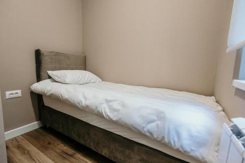 an unmade bed with white sheets and a pillow at Pansion "Fawlty Towers" Sarajevo in Sarajevo