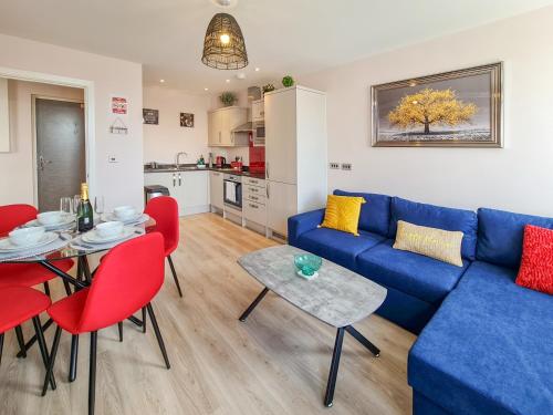 a living room with a blue couch and red chairs at The Post House Green by Fortuna Property Portfolio in Gloucester