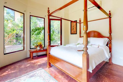 a bedroom with a four poster bed and windows at Morningstar Breeze Gold Standard Certified in Hopkins