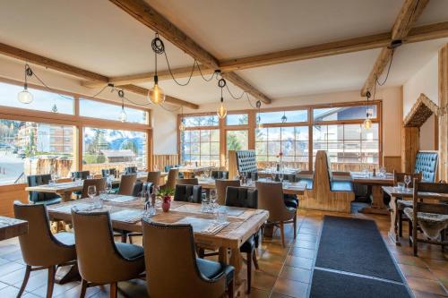 a restaurant with wooden tables and chairs and windows at PAPILL'ON - Boutique Hotel in La Tzoumaz