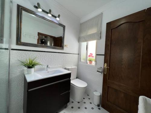 a bathroom with a sink and a toilet and a mirror at Casa Azalea - nuevo alojamiento en Setenil de las Bodegas in Setenil