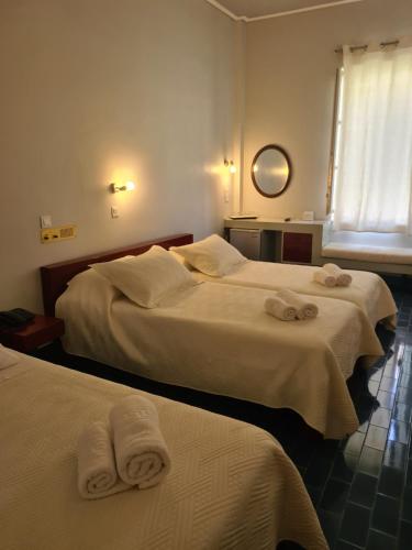 Greco Hotel في هيدرا: سريرين في غرفة الفندق عليها مناشف