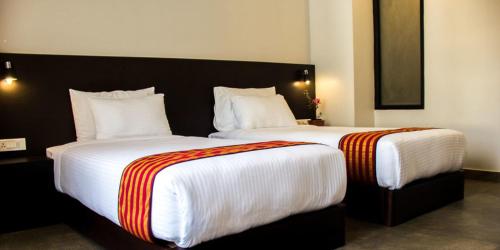 Un dormitorio con dos camas con sábanas blancas y rayas naranjas. en Hotel Bhutan Ga Me Ga, en Phuntsholing