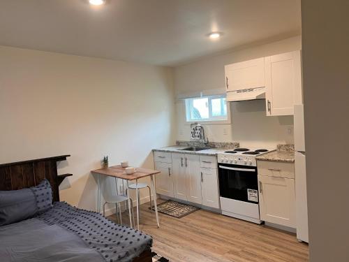 una cucina con armadi bianchi, tavolo e letto di Studio apartment a Cranbrook