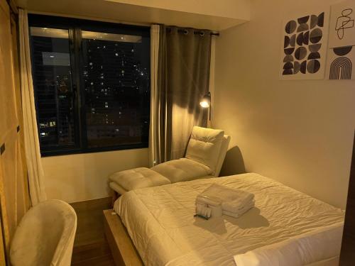 a bedroom with a bed and a chair and a window at Destina Stays, Cozy & Netflix @Air Residences, Makati, Metro Manila in Manila