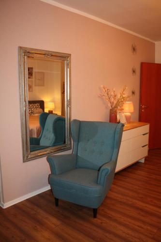 a room with a blue chair and a mirror at Kikelet Udvarház in Zánka