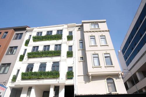 ein hohes weißes Gebäude mit grünen Pflanzen darauf in der Unterkunft AB Residences -Cihangir Luxury Sapphire Apartment in Istanbul