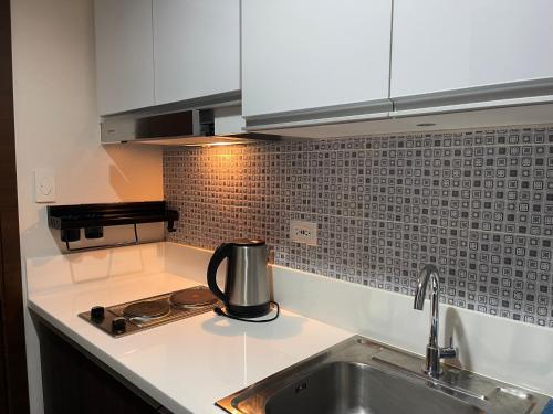 a kitchen counter with a sink and a stove at Destina Stays, Cozy & Netflix @Air Residences, Makati, Metro Manila in Manila