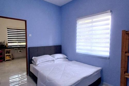 1 dormitorio con 1 cama blanca y ventana en Singgah Homestay en Kuala Terengganu