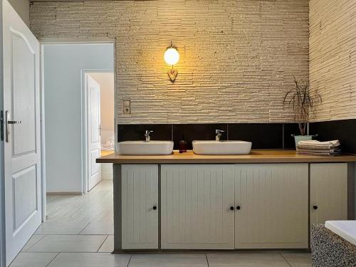a bathroom with two sinks and a brick wall at Rekreačný domček TIŽINA in Terchová