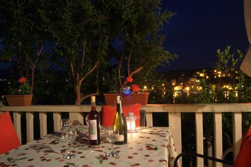 a table with wine bottles and glasses on a balcony at night at Apartments Tereza in Koločep