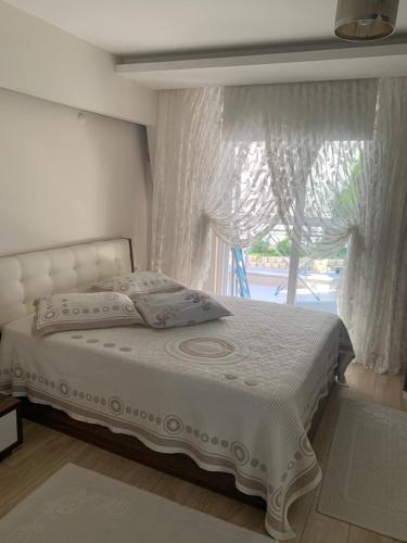 1 dormitorio con 1 cama y una ventana con cortinas en Mudanya Falez Evleri. en Mudanya