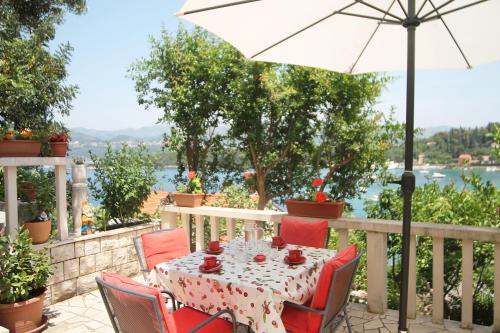 a table and chairs on a balcony with an umbrella at Apartments Tereza in Koločep