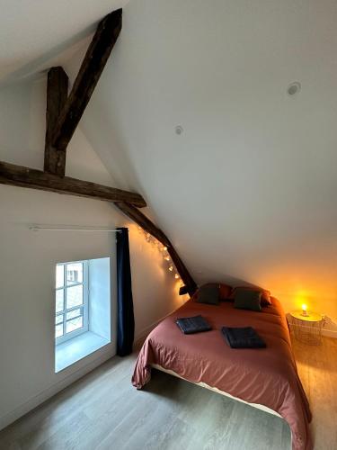 ein Schlafzimmer mit einem Bett und einem Fenster im Dachgeschoss in der Unterkunft T2 atypique et chaleureux in Baugé