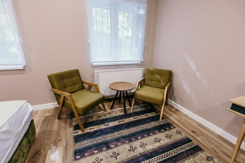 two chairs and a table in a room with a rug at Pansion "Fawlty Towers" Sarajevo in Sarajevo