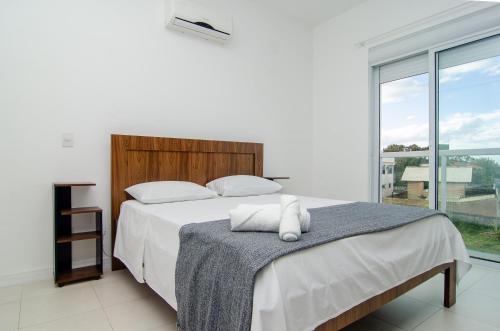 a bedroom with a bed and a large window at Apto Vista Mar com acesso a Praia do Santinho QM9528 in Florianópolis