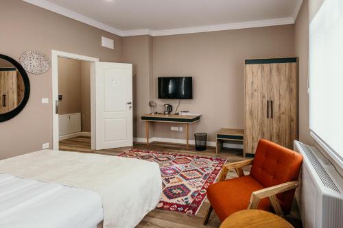 a bedroom with a bed and a chair and a desk at Pansion "Fawlty Towers" Sarajevo in Sarajevo