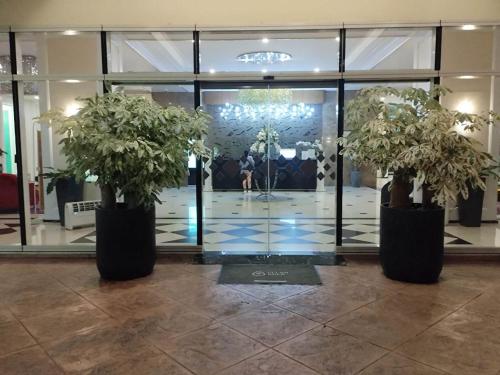 a lobby with two potted plants in front of a building at Homey Studio at Stamford Mckinley hill few walk to Venice Piazza in Manila