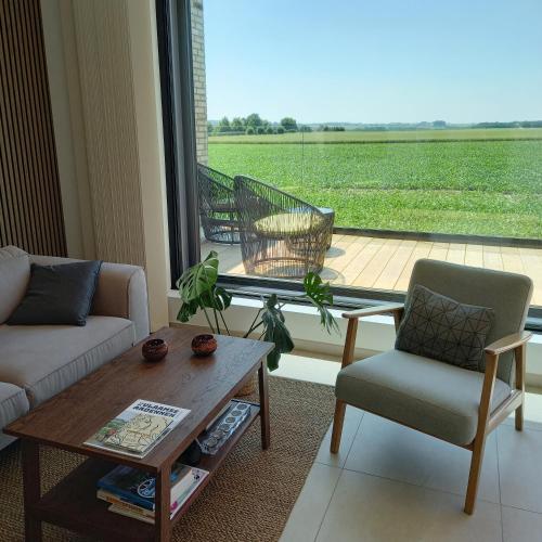 a living room with a table and chairs and a large window at De Molenlos in Zottegem