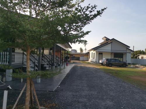 ein Gebäude mit einem Auto neben einem Baum in der Unterkunft Anjung Barakah Chalet in Kuala Terengganu