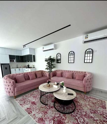 a living room with two pink couches and a table at إيفا شالية in Mu‘tamar