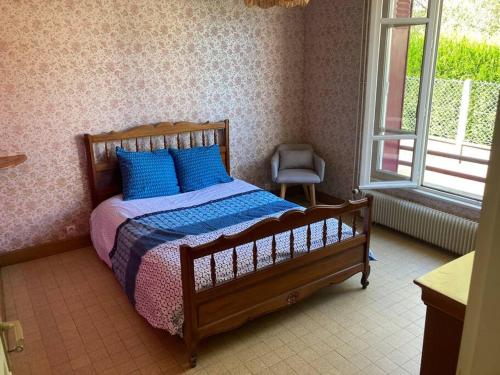 a bedroom with a wooden bed with blue pillows at Longère du Perche in Montigny-le-Chartif