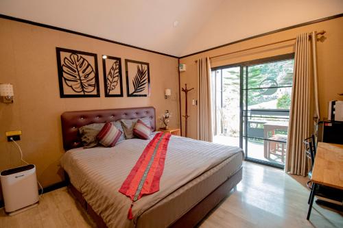 a bedroom with a bed and a large window at ฟินอินดอย in Chom Thong