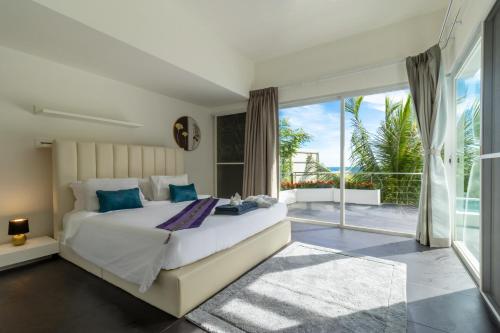 a bedroom with a large bed and a balcony at Cozy 5BR Villa Stunning SeaViews in Kamala Beach