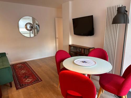 a living room with a table and red chairs at Midtown London Apartment in London