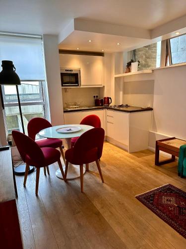 Midtown London Apartment في لندن: غرفة معيشة مع طاولة وكراسي ومطبخ