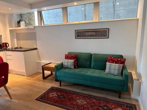 Midtown London Apartment في لندن: غرفة معيشة مع أريكة خضراء وطاولة