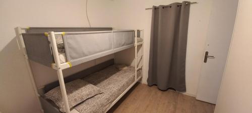 a small room with a bunk bed with a curtain at Adorable maison dans le port in Port-Vendres