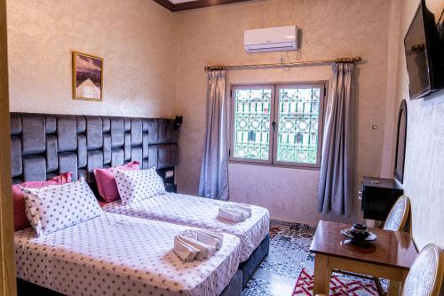 a bedroom with a bed and a couch and a window at HOTEL LA VALLEE DES KASBAHS CHEZ ILYAS in Tinerhir